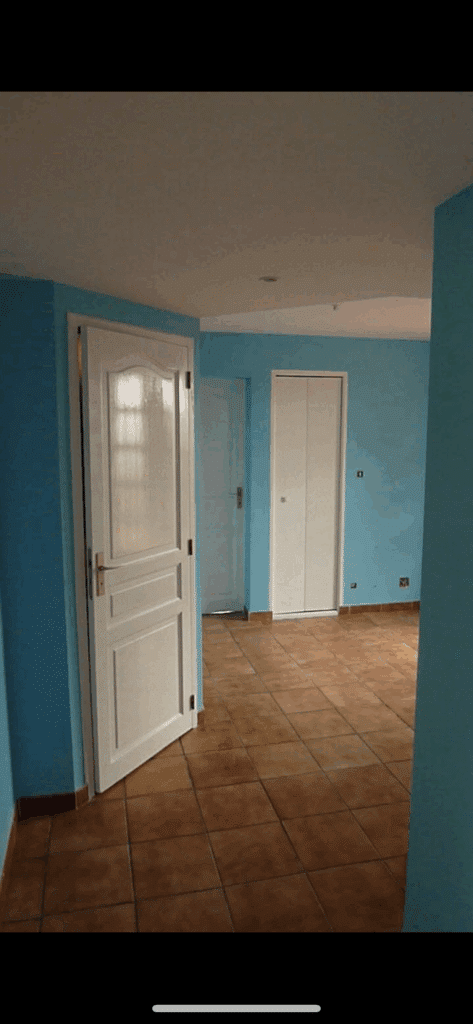 Couloir Lumineux: Murs Bleus, Portes Blanches et Carrelage Couloir intérieur lumineux avec murs bleu ciel et carrelage terre cuite. Trois portes blanches : une ouverte à gauche, deux fermées, dont un placard.