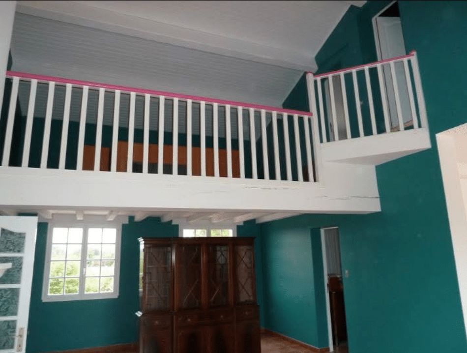 Mezzanine Moderne: Salon Vert Canard & Balustrade Rose Intérieur vert canard, mezzanine blanche avec balustrade rose. Fenêtres, extérieur verdoyant et buffet en bois foncé.