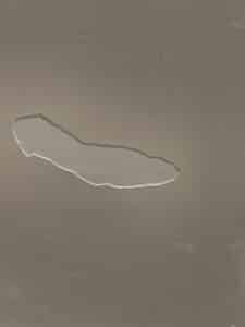 Peinture beige ou grège écaillée sur une surface murale, formant une longue déchirure irrégulière révélant l'enduit inférieur.